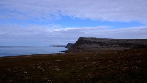 View of calm beach against cloudy sky
