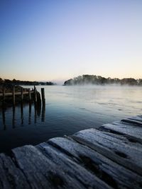 Pier over lake against clear sky during sunset