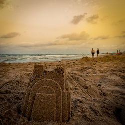 Close-up of sandcastle on beach against sky during sunset