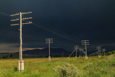 Electricity pylon on field against sky