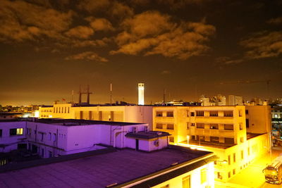 Illuminated factory against sky at night