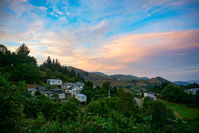 Houses in town against sky during sunset