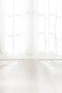 Sunlight pouring through french doors with white curtains onto wooden floor in home 