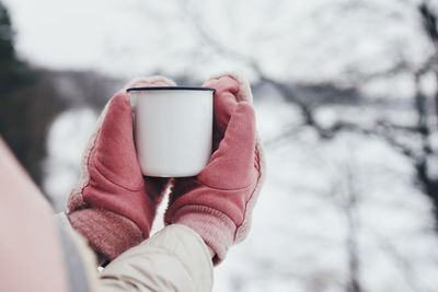 Midsection of person holding smart phone during winter