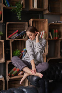 Woman sitting against shelf