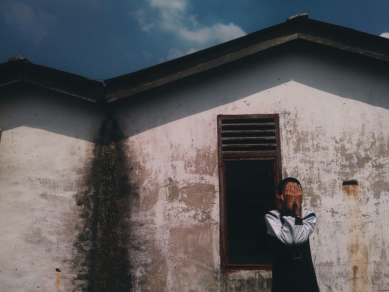 architecture, building exterior, built structure, lifestyles, young adult, leisure activity, low angle view, sky, casual clothing, person, building, standing, day, religion, wall - building feature, outdoors, old, sunlight
