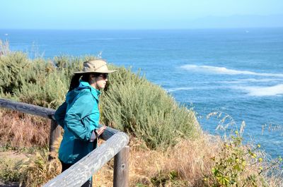 Woman standing at observation point by sea against sky