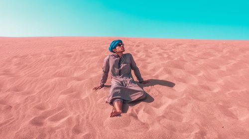 Full length of man on sand in desert against sky