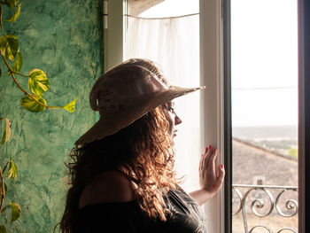 Side view of woman looking through window