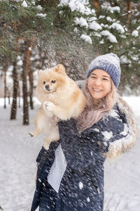 Portrait of smiling woman with snow in forest during winter