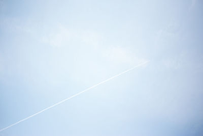 Low angle view of vapor trails against blue sky