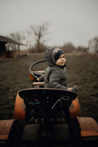 Boy sitting on snow covered land