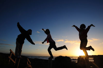 Woman jumping in water at sunset