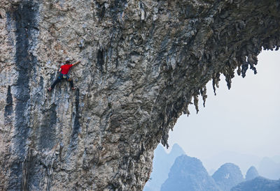 Man climbing on the natural rock arch on moon hill in yangshuo