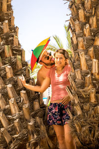 Man licking girlfriend amidst tree trunks