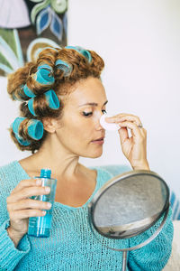 Close-up of mature woman applying make-up against white background