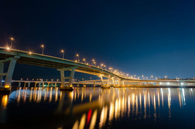 Illuminated bridge over river at night