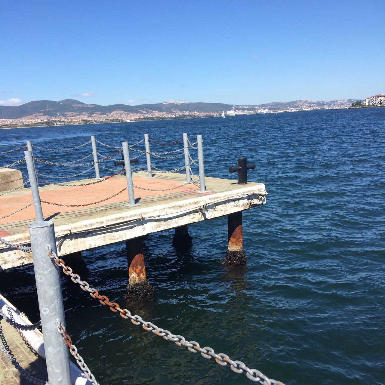 water, pier, blue, built structure, damaged, architecture, tranquil scene, tranquility, sea, mountain, clear sky, scenics, jetty, deterioration, horizon over land, day, engineering, obsolete, non-urban scene, nature, outdoors, mountain range, sky, weathered, beauty in nature