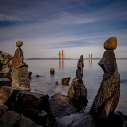 Rocks on sea shore against sky during sunset