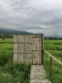 Wooden structure on field against sky
