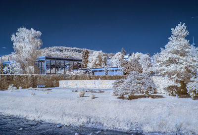 Snow covered field against clear blue sky