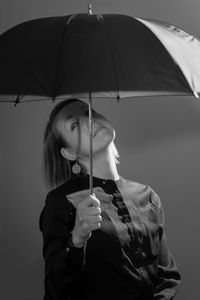 Portrait of woman under umbrella against gray background