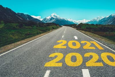 Text on road by mountain against sky