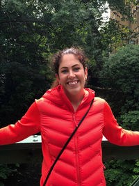 Portrait of smiling young woman standing against trees