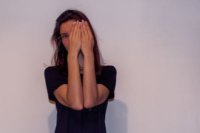 Beautiful young woman standing against white background