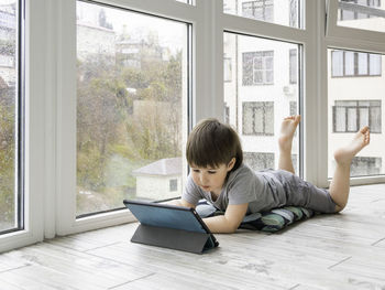 Side view of boy using laptop while sitting on floor at home