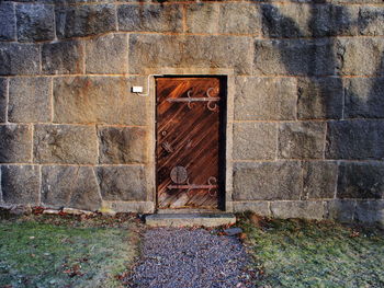 Closed rusty door amidst concrete wall