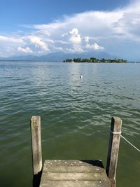 Wooden posts in sea against sky