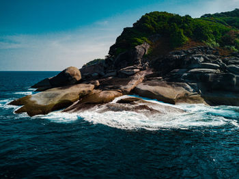 Rock formation on beach against sky