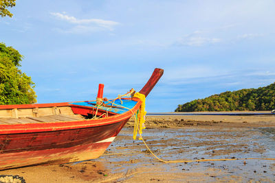 Boat moored on beach against sky