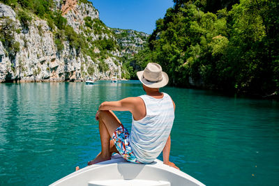 Rear view of man sitting on boat in lake