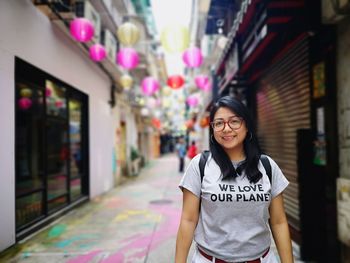 Portrait of smiling woman standing on narrow street