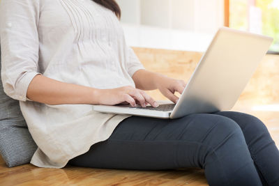 Midsection of woman using mobile phone at home