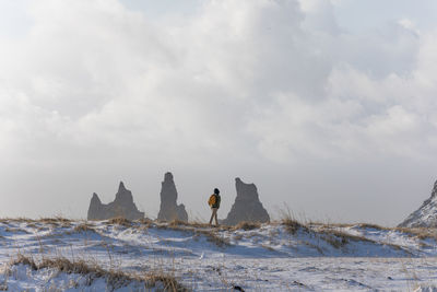 People on snow covered landscape against sky