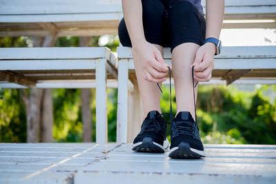 Low section of woman tying shoelace at park