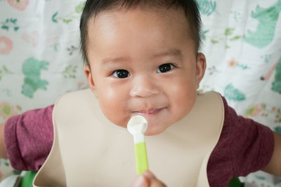 A happy asian baby boy sitting and feeding some pap pudding by mom with spoon.