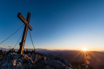 Windmill on rock against sky during sunset