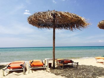 Deck chairs on beach against sky