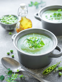 Fresh green pea soup bowl on gray concrete background