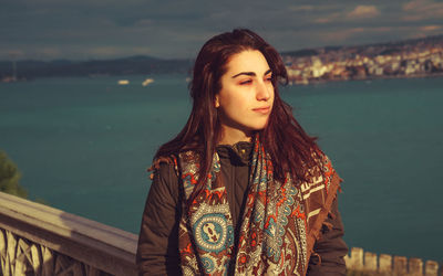 Close-up of young woman standing by sea against sky