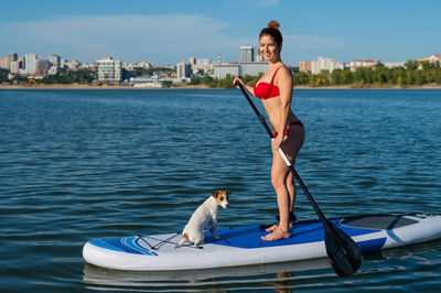 Portrait of smiling woman with dog paddleboarding