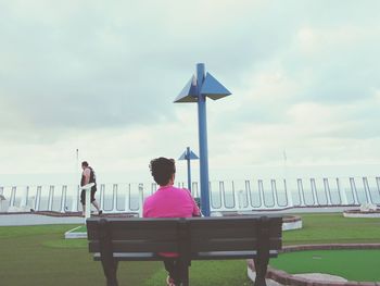 Rear view of woman sitting on bench at golf course in cruise ship