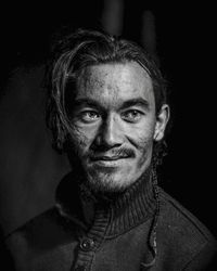 Close-up portrait of smiling man against black background