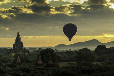 Hot air balloons on field against sky during sunset