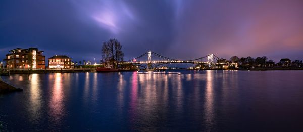 View of illuminated bridge over river at night