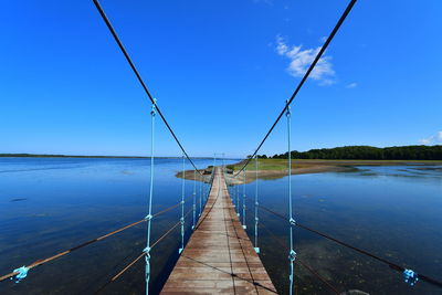 Footbridge over water against blue sky